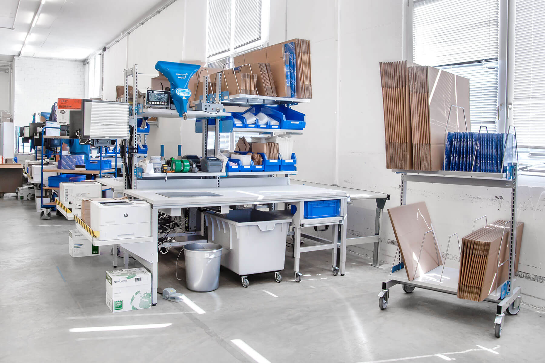 Tables d'emballage ERGO-Basic le long d'un convoyeur à rouleaux